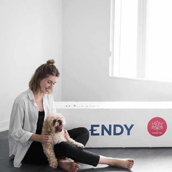 Woman petting her dog next to Endy Mattress box