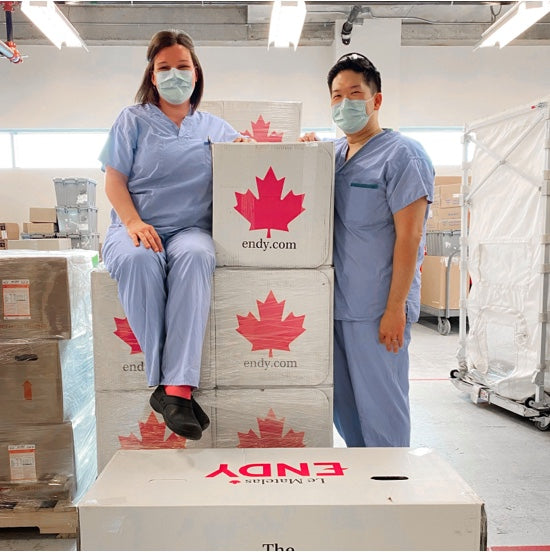 Two Abbotsford Hospital healthcare workers wearing scrubs and posing with Endy Mattress boxes.