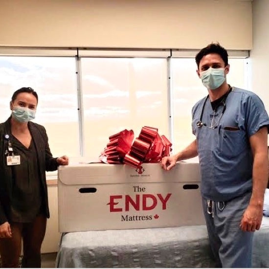 Two Southlake Hospital healthcare workers wearing scrubs and posing with an Endy Mattress box.