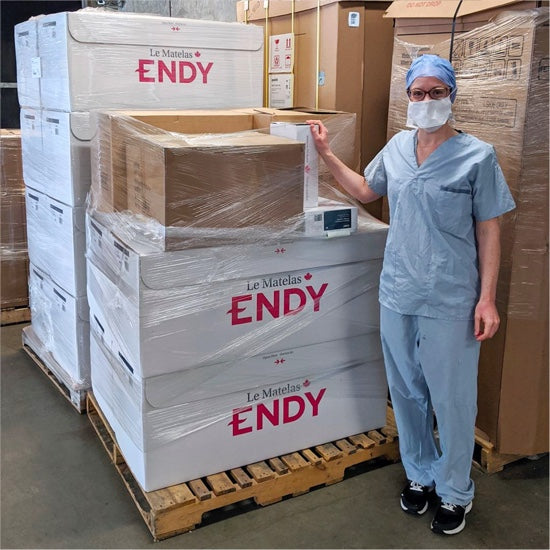 One St.Pauls's Hospital healthcare worker wearing scrubs and posing with a new delivery of Endy Mattresses.